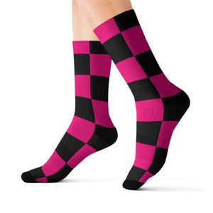 Peut inclure: Chaussettes hautes aux genoux avec un motif à carreaux audacieux en noir et rose vif. Le motif est une grille répétée de carrés alternés, couvrant les pieds et le bas des jambes. Design accrocheur.