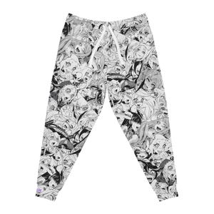 Può includere: Pantaloni della tuta in bianco e nero con un'illustrazione ripetuta in stile manga. I pantaloni hanno una vita con coulisse e polsini alle caviglie. La grafica presenta vari volti in stile anime.