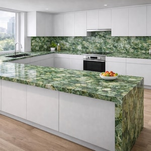 May include: Modern kitchen with white cabinets and a large island featuring a green, patterned countertop. The countertop extends to the backsplash. A bowl of fruit sits on the island. The floor is light wood.