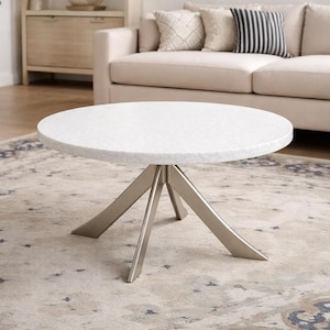 Può includere: Un tavolino rotondo con un piano bianco maculato e una base in metallo spazzolato. Il tavolo ha un design moderno ed è posto su un tappeto fantasia. Il diametro del tavolo è di circa 90 cm.