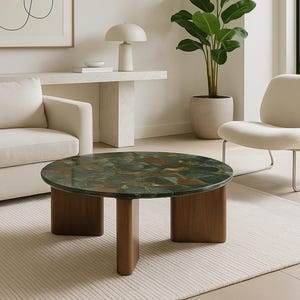 Könnte beinhalten: Ein runder Couchtisch mit einer grün-braunen Steinplatte und einem Holzsockel. Der Tisch steht in einem Wohnzimmer mit einem weißen Sofa, Stuhl und Teppich. Der Raum hat ein modernes Design.