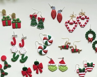 May include: A collection of holiday-themed dangle earrings featuring various designs including red and green gift boxes, Christmas trees, candy canes, wreaths, peppermint swirls, dachshunds, bows, holly, Santa hats, and striped mouse ears.