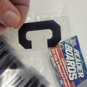 Puede incluir: Una letra "C" negra, de forma octogonal, sobre una l&aacute;mina de pl&aacute;stico transparente, sostenida por una mano. La imagen tambi&eacute;n muestra una pila de l&aacute;minas similares y un letrero de Reader Boards con el texto: "American Style Changeable Signs DIY Kits & Bespoke Projects."