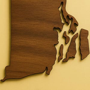 May include: A wooden map of Rhode Island, USA, with a detailed grain pattern. The state's outline is cut from a dark brown wood, set against a light yellow background. The map includes the mainland and islands.