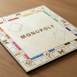 Op de afbeelding: Houten Monopoly-bord met kleurrijke eigendomsruimtes en het woord "MONOPOLY" in het midden. Het bordspel bevat klassieke eigendomsruimtes, Kans- en Gemeenschapsfondsgebieden en de Start-ruimte. Het bord ligt op een houten oppervlak.
