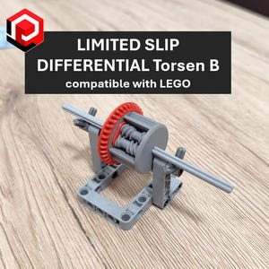 May include: A grey and red Limited Slip Differential Torsen B, compatible with LEGO, is shown on a wooden surface. The text "LIMITED SLIP DIFFERENTIAL Torsen B compatible with LEGO" is printed on a black rectangle. The differential has a red gear.