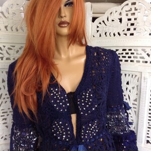 May include: A navy blue crocheted cardigan with a tie closure and embellished with rhinestones. The cardigan has long sleeves and a loose fit.