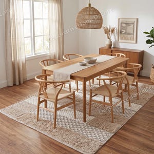 Puede incluir: Un juego de comedor con una mesa de madera clara y seis sillas. Las sillas tienen asientos tejidos y respaldos curvos. Una alfombra estampada y una lámpara colgante tejida completan la decoración de la habitación.