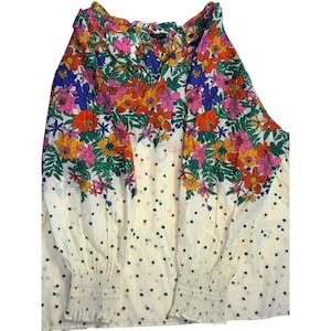 May include: A long-sleeved blouse with a V-neck and floral print. The top features a white base with colorful flowers in shades of pink, orange, yellow, and blue. The sleeves have elastic cuffs. The blouse is a women's top.