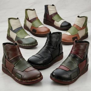 以下が含まれることがあります： 黒、茶色、緑、クリーム色など、さまざまな色のアンクルブーツのコレクション。ブーツは、革のパネルとローヒールを備えたパッチワークデザインです。ブーツは、大理石の表面に表示されています。