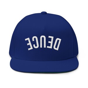 Può includere: Un berretto da baseball blu reale a tesa piatta con la scritta bianca "DEUCE" ricamata sul davanti. Il berretto ha una vestibilità strutturata e una visiera curva. Un accessorio elegante.