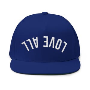 Può includere: Un berretto da baseball blu reale a tesa piatta con la scritta bianca ricamata "LOVE ALL" sul davanti. Il berretto ha una corona strutturata e una visiera piatta. Il berretto è di colore pieno con un lato inferiore verde.