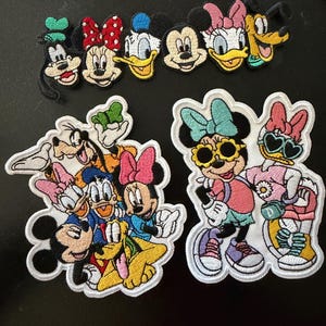 以下が含まれることがあります： ディズニーキャラクターの刺繍ワッペン3枚。上段はグーフィー、ミニーマウス、ドナルドダック、ミッキーマウス、デイジーダック、プルート。左下のワッペンはグループ全員、右下はミニーとデイジーが描かれています。