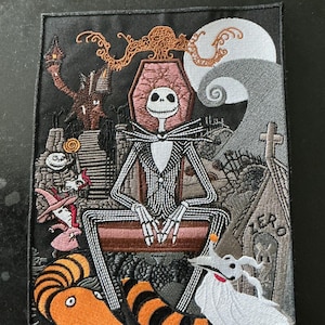 May include: A rectangular embroidered patch featuring a skeleton character in a pinstripe suit sitting on a coffin. The scene includes a full moon, a graveyard, a ghost dog, and a snake with orange and black stripes. The text ZERO is visible.