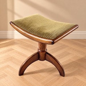 Op de afbeelding: Een kruk met een gebogen frame van donker hout en een gestructureerde, olijfgroene gestoffeerde zitting. De basis heeft drie gebogen houten poten die samenkomen bij een centrale kolom, wat een stabiele ondersteuning biedt voor het concave zitvlak.