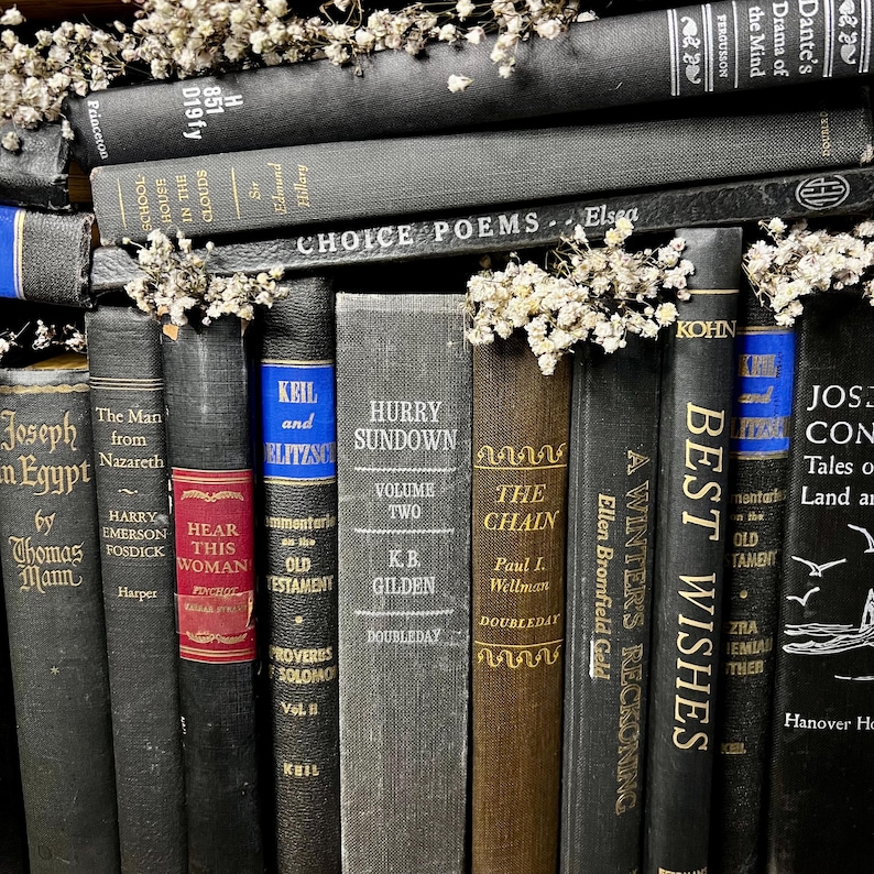 May include: A selection of vintage books with dark spines, including black, brown, and blue. The books are adorned with small white flowers, creating a classic look. Titles include "Choice Poems" and "Best Wishes".