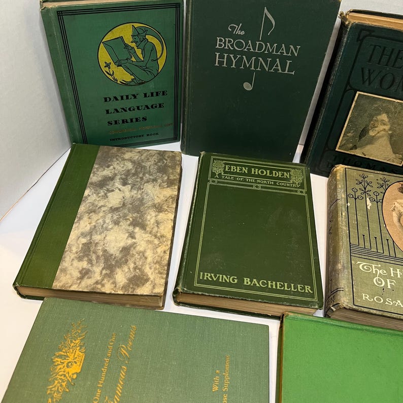 May include: A collection of vintage books with green covers. Titles include "Daily Life Language Series," "The Broadman Hymnal," and "Eben Holden." The books vary in size and design, with some featuring gold lettering and illustrations.