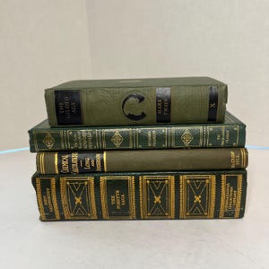 May include: A stack of four vintage books with green and gold covers. Titles include "The Gilded Age," "The Forsyte Saga," and "Chemical Calculations." The books are arranged in a neat pile, showcasing classic literature.