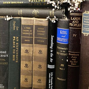 May include: A selection of antique books with diverse titles and colours. The spines are in shades of brown, black, and tan, with gold lettering. Some books feature decorative elements and floral accents. Titles include "A Tree Grows in Brooklyn" and "Something in the Air."