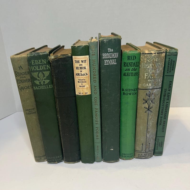 May include: A collection of vintage books with green and dark covers. Titles include "Eben Holden," "The Wit and Humor of America," and "The Broadman Hymnal." The books are arranged in a row, showcasing their aged appearance.