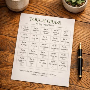 May include: A 30-day digital detox plan titled "Touch Grass" is displayed on a white paper, with a coffee mug and a small succulent plant. A black and gold pen rests on the wooden surface.
