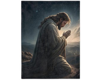 May include: A rectangular throw blanket featuring a serene illustration of a figure kneeling in prayer. The figure is draped in a light-colored robe, with a halo and a starry night sky backdrop. The artwork evokes a sense of peace and spirituality.