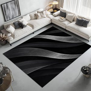 May include: A large, rectangular area rug with a wavy, textured design in shades of black, gray, and white. The rug's pattern creates a sense of depth and movement, suitable for a living room or similar space.