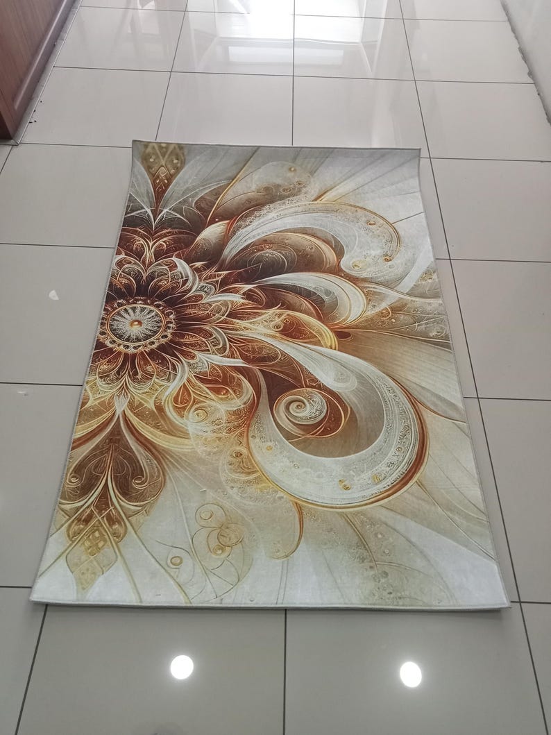 Op de afbeelding: Een rechthoekig vloerkleed met een groot, ingewikkeld, op bloemen ge&iuml;nspireerd fractaalpatroon in tinten donkerbruin, koper, goud en cr&egrave;me. Het ontwerp straalt uit vanuit een centraal cirkelvormig motief met wervelende, organische lijnen.