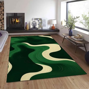 Op de afbeelding: Een rechthoekig vloerkleed met een abstract ontwerp in groen- en crèmetinten. Het vloerkleed heeft een golvend patroon, waardoor een gevoel van beweging ontstaat. Het vloerkleed ligt op een houten vloer in een woonkamer. De afmetingen zijn niet zichtbaar.