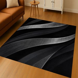 Puede incluir: Una alfombra rectangular con fondo negro y un patrón ondulado en tonos grises y blancos. El diseño crea una sensación de movimiento y profundidad, adecuada para una sala de estar o dormitorio, con estética moderna.