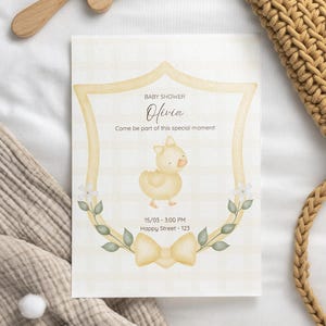 Puede incluir: Una invitaci&oacute;n para baby shower con un dise&ntilde;o de escudo amarillo, con una ilustraci&oacute;n de pato y detalles florales. La invitaci&oacute;n incluye el nombre "Olivia" y el texto "Come be part of this special moment!" y la fecha y hora.