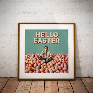 May include: A framed art print with a retro design. The image shows a man seated amongst pastel Easter eggs, drinking from a mug. The words "HELLO EASTER" are displayed in a vintage font against a teal background.