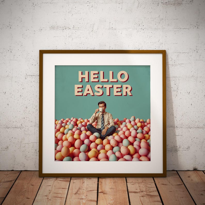 May include: A framed art print with a retro design. The image shows a man seated amongst pastel Easter eggs, drinking from a mug. The words "HELLO EASTER" are displayed in a vintage font against a teal background.