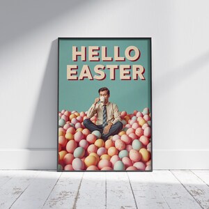 May include: A framed art print featuring the text "HELLO EASTER" in red and white. The image depicts a person seated amidst a pile of pastel Easter eggs, sipping from a white mug. The backdrop is a teal hue.