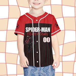 Pode incluir: Camisola de baseball vermelha e preta com o texto "SPIDER-MAN Miles Morales 00". A camisola tem detalhes brancos, um logotipo do Homem-Aranha nas mangas e um design listrado preto e vermelho na frente.