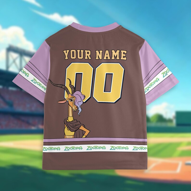 May include: Brown and lavender baseball jersey featuring a cartoon gazelle character. The jersey has the text "YOUR NAME" above the number "00" in gold. The sleeves are lavender with "Zootopia" printed on them. The bottom of the jersey also has "Zootopia" printed on it.