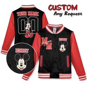 May include: Black and red varsity jacket featuring Mickey Mouse. The jacket has red sleeves, a black body, and white and red striped trim. The front displays Mickey Mouse and the word "Mickey". The back has the text "YOUR NAME" and the number "00".