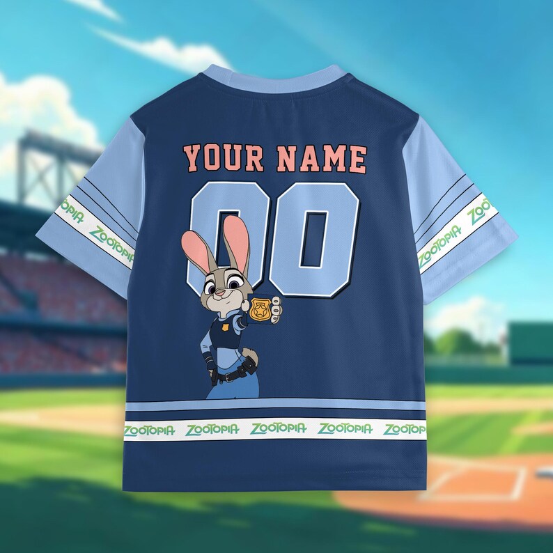 Puede incluir: Camiseta de b&eacute;isbol azul marino con el personaje de Zootopia Judy Hopps. La camiseta tiene mangas azul claro y cuello azul claro. La parte trasera muestra el texto "YOUR NAME" sobre el n&uacute;mero "00". La parte inferior tiene el texto "Zootopia".