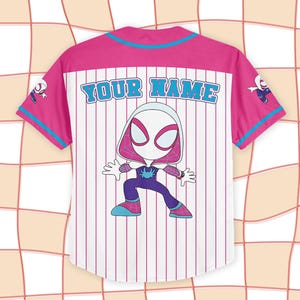 May include: White baseball jersey with pink and blue accents. Features a cartoon Spider-Gwen character on the back, with the text "YOUR NAME" above the character. The jersey has vertical pink stripes.
