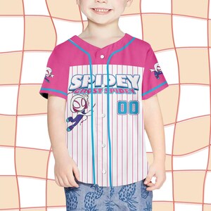 May include: A pink and white baseball jersey with the text "Spidey and Ghost Spider" and the number "00". The jersey has blue accents and cartoon graphics of the character. The jersey is worn by a child.