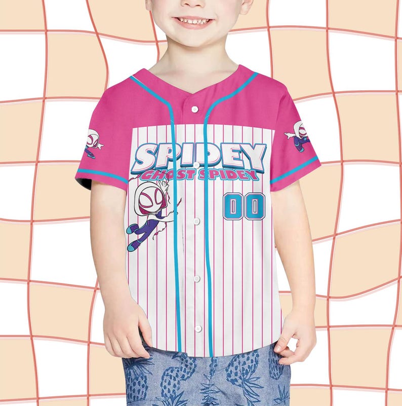 May include: A pink and white baseball jersey with the text "Spidey and Ghost Spider" and the number "00". The jersey has blue accents and cartoon graphics of the character. The jersey is worn by a child.
