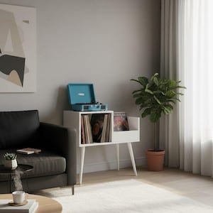 Könnte beinhalten: Ein weißer Plattenspieler-Ständer im Mid-Century-Modern-Stil mit einem türkisfarbenen Plattenspieler. Der Ständer hat ein Fach für Schallplatten und ein kleines Regal. Eine Topfpflanze und ein schwarzes Sofa befinden sich ebenfalls im Raum.