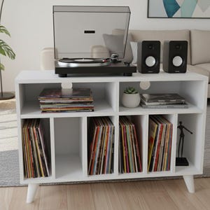 May include: White vinyl record storage cabinet with a turntable, speakers, and a stack of records. The cabinet has multiple compartments filled with vinyl records. A potted plant and a decorative figurine are also visible.