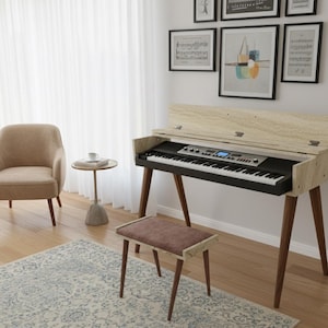 Könnte beinhalten: Ein Digitalpiano in hellen Holztönen mit schwarzer Tastatur und dunkelbraunen Beinen. Eine passende Bank mit braunem Kissen steht davor. Das Klavier befindet sich in einem Raum mit einem beigefarbenen Sessel, einem kleinen Beistelltisch und einem gemusterten Teppich.