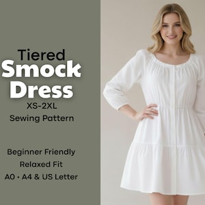 May include: A white tiered smock dress sewing pattern, XS-2XL, with a relaxed fit. The image shows a woman wearing the dress. The text on the left says "Tiered Smock Dress" and "Sewing Pattern".