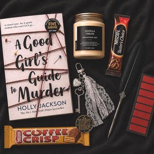 May include: An assortment of items on a black surface, including a book titled "A Good Girl's Guide to Murder", a jar of vanilla cream, a keychain, a pen, a candy bar, and a coffee packet. The book is by Holly Jackson.