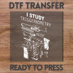 May include: A DTF transfer featuring a white line-art diagram of a disassembled handgun with numbered parts. The text reads I STUDY TRIGGERNOMETRY in a bold, distressed font. The design is presented on a dark gray square background.