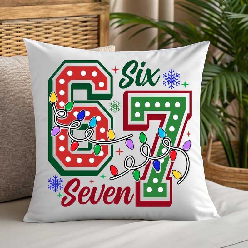 A white pillow with a colorful design featuring the numbers '67' and '67' surrounded by Christmas lights and snowflakes.