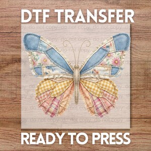 May include: A colorful butterfly design, ready to press, with the text "DTF TRANSFER" and "READY TO PRESS". The butterfly features patchwork wings in shades of blue, yellow, pink, and floral patterns. The background is a light wood grain.