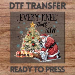 May include: DTF transfer design featuring Santa Claus kneeling before baby Jesus in a manger, with a decorated Christmas tree. The text reads "Every Knee Shall Bow" and "Philippians 2:10". The design is ready to press.